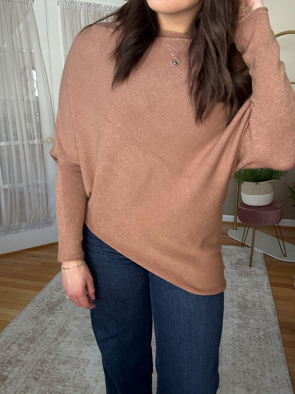 Woman wearing soft wool blend camel assymetrical off the shoulder sweater that is made in Italy