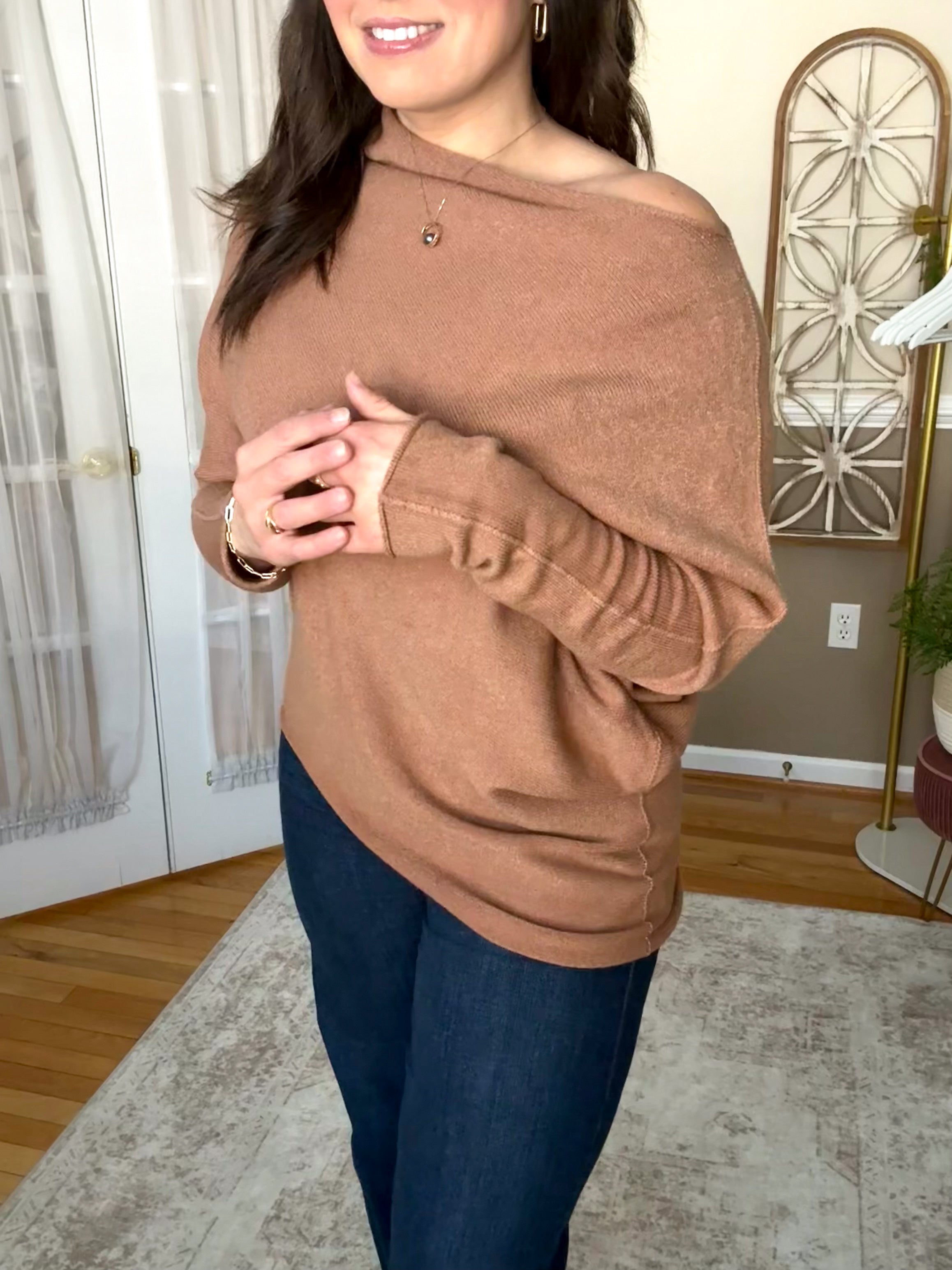 Woman wearing soft wool blend camel assymetrical off the shoulder sweater that is made in Italy